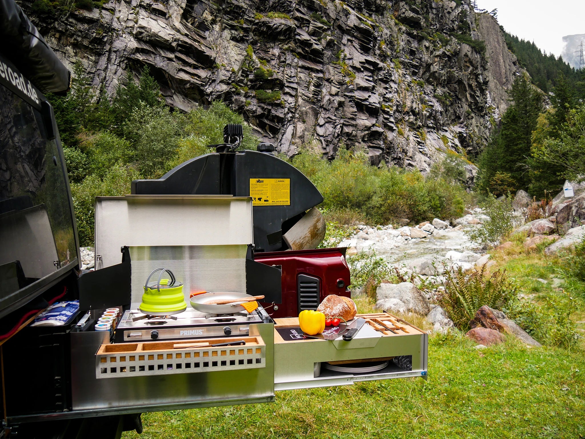 Mobile Küchenbox MOKUBO Heckauszug längs im Jeep Wrangler vor Fels Massiv und Bach