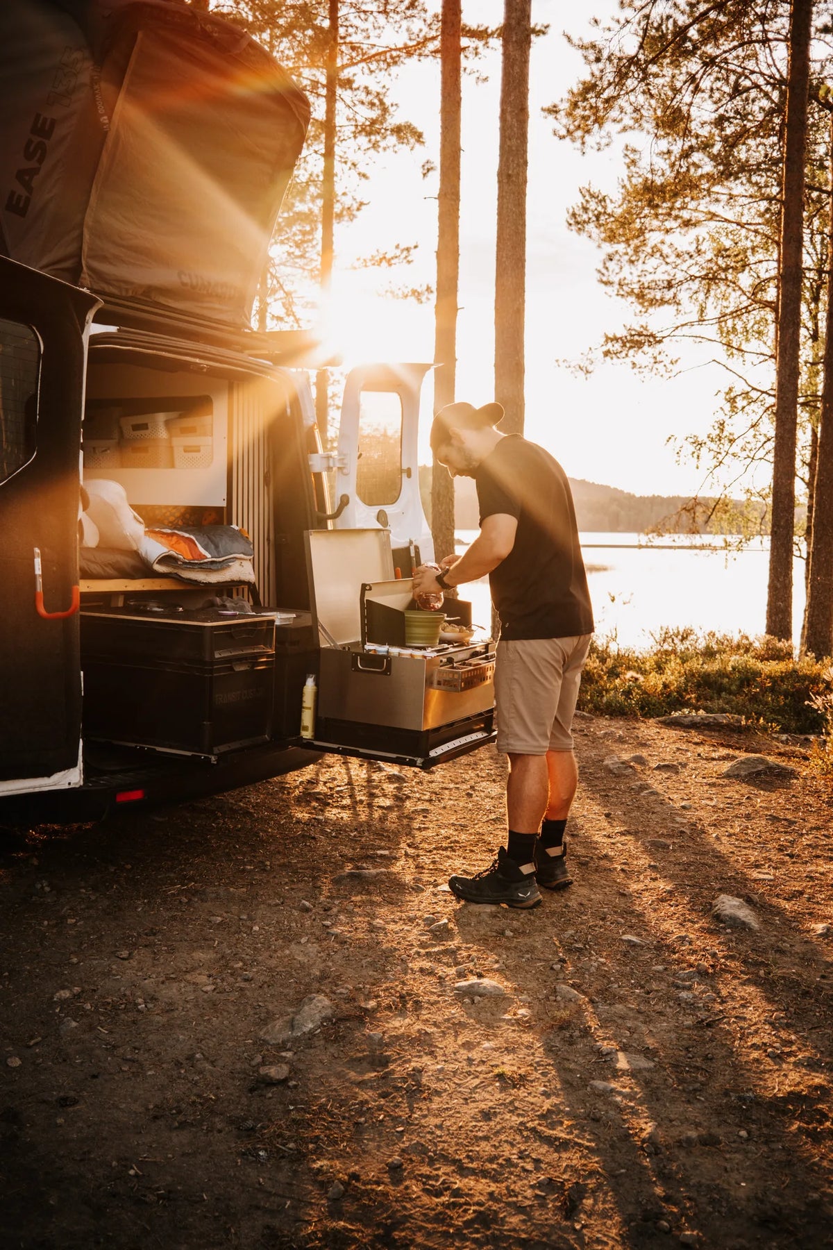 Kochen mit der mobilen Küchenbox MOKUBO am Heck eines Campervans am See in der Abendsonne