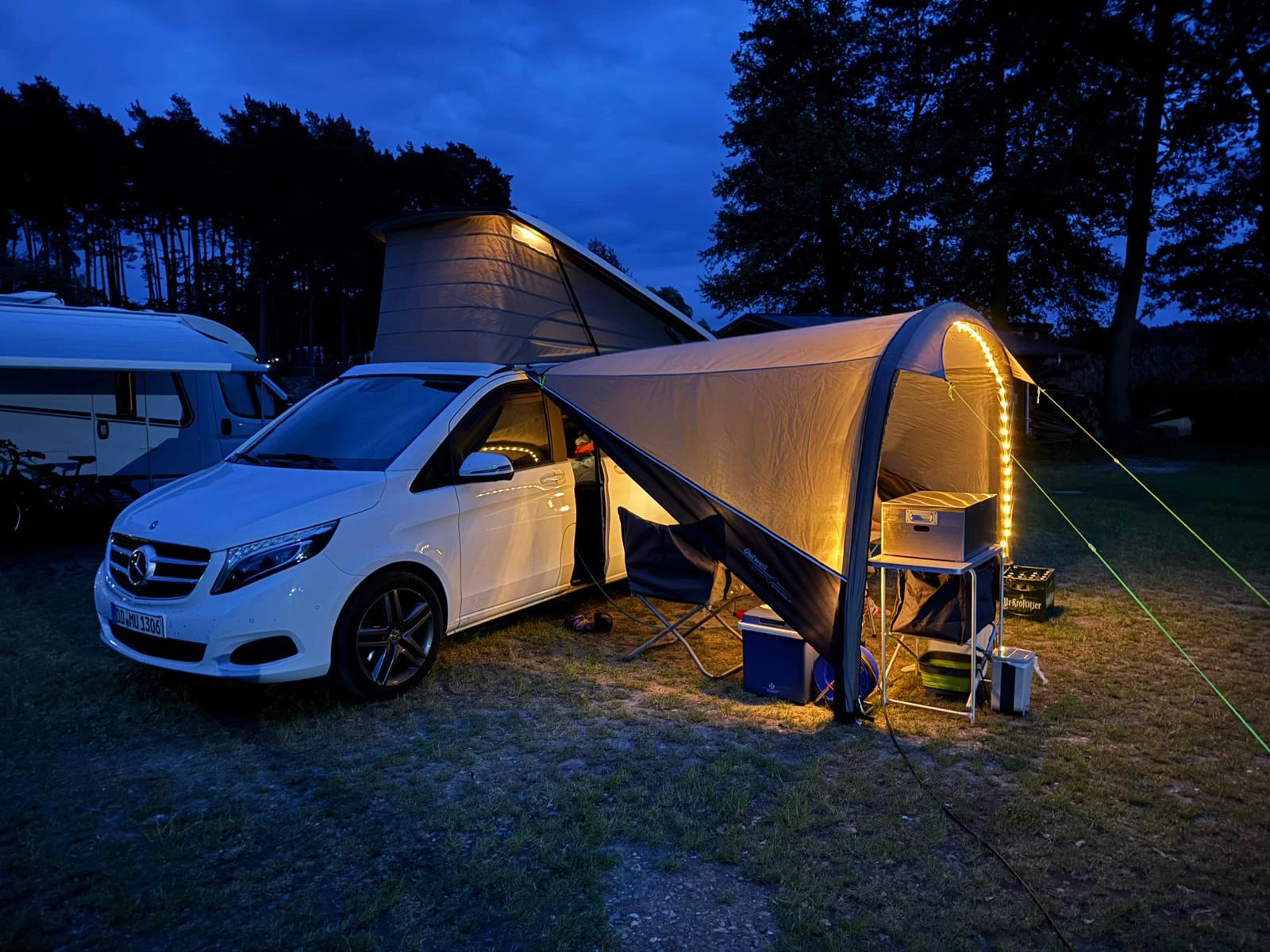 Mobile Küchenbox MOKUBO im Mercedes V-Klasse Vorzelt auf Tisch am Abend beleuchtet